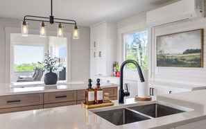 Eine moderne Küche mit einer großen Kochinsel, einem schwarzen Wasserhahn und einem Fenster mit Ausblick.