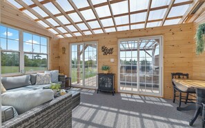 A cozy room with a wooden interior, a sofa, a table, and a fireplace. - Spacious 6 BR Water view home - Sleeps 11 - Private - Near beach (Mount Stewart)