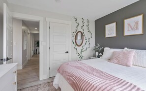 A bedroom with a bed, bedside table, and a door leading to another room.