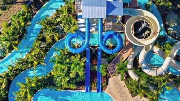 Un parco acquatico con diverse scivolate e piscine, circondato da palme.