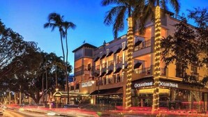 Un hotel a più piani con balconi, un ristorante chiamato 'Ocean Prime' e palme.