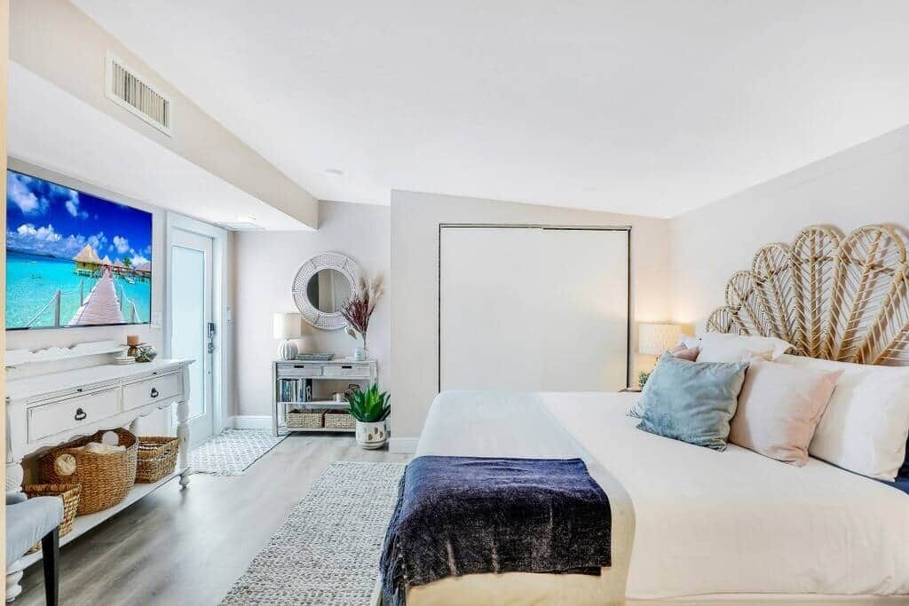 Une chambre à coucher avec un lit, une télévision, une commode et un miroir.