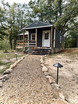 A cabin with a front porch, a wooden deck, and a gravel pathway leading to the entrance. - Little River Hideout - Two Cabins on Little River (Cedar Bluff)