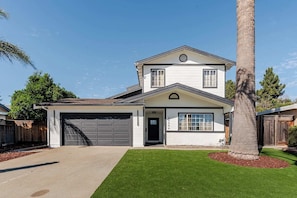 A two-story house with a garage, a front door, and a small porch.