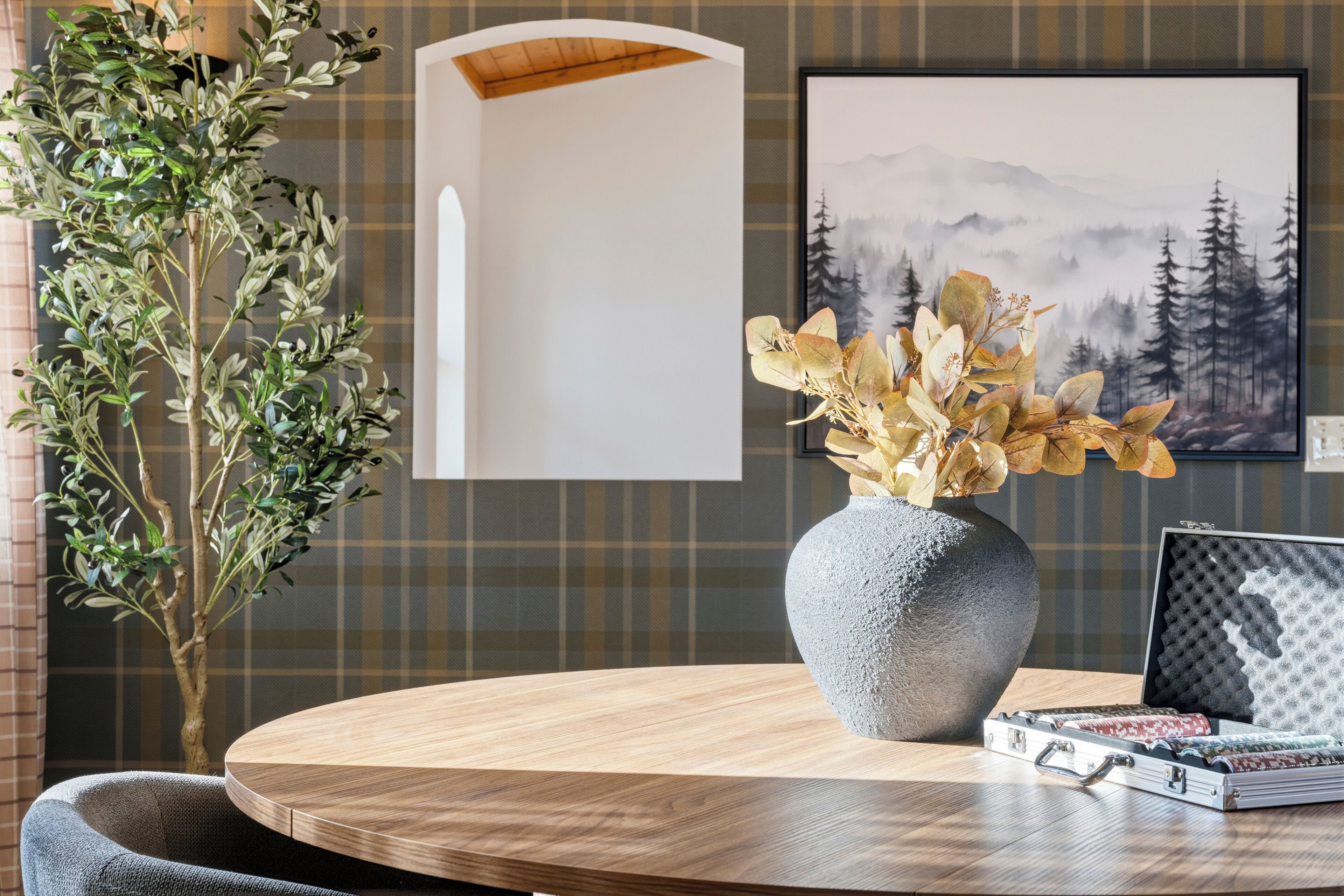 A round wooden table with a grey vase and a metal case.
