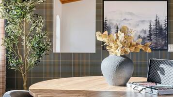 A round wooden table with a grey vase and a metal case.