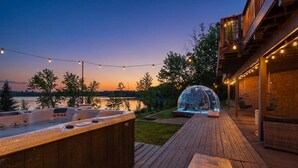 Een hottub en terras met lichtjes, met uitzicht op een meer.