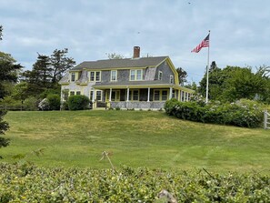 A two-story house with a porch, a flag, and a well-maintained lawn. - North Chatham Beachwalk -Spacious 6 bedroom walk to beach sprawling private yard (Chatham)