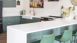 A modern kitchen with a central island, green chairs, a clock, and a rustic painting. - 2 Waterfront Houses |Jacuzzi |Dock For Boat|Groups (New Haven)