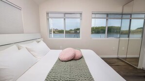 A bedroom with a bed, a green blanket, and two pink pillows. - 2 Waterfront Houses |Jacuzzi |Dock For Boat|Groups (New Haven)