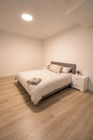 Ein Schlafzimmer mit Bett, Nachttisch und einer kleinen Pflanze.