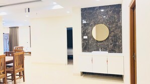 Une salle de bain moderne avec un comptoir en marbre, un miroir rond et un lavabo blanc.
