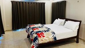 Une chambre d’hôtel équipée d’un lit, de rideaux, d’un climatiseur et d’un ventilateur de plafond.