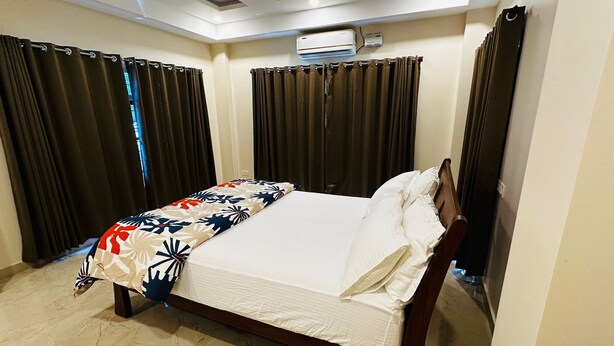 Une chambre d’hôtel équipée d’un lit, de rideaux, d’un climatiseur et d’un ventilateur de plafond.