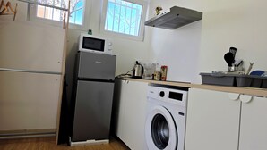 Kompakti keittiö, jossa on jääkaappi, mikroaaltouuni ja pesukone.