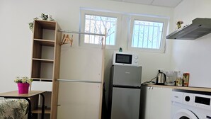 Pieni, käytännöllinen keittiö, jossa on jääkaappi, mikroaaltouuni, pesukone ja pieni ikkuna.