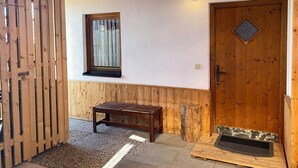 A wooden interior with a bench, a door, and a window.