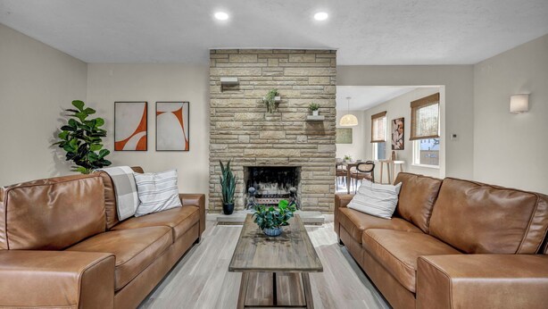 A living room with two leather sofas, a coffee table, a stone fireplace, and a potted plant. - Bright 2BR w/ Sunroom Near Downtown & Beach (Euclid)
