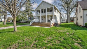 A two-story house with a front porch, a driveway, and a lawn. - Bright 2BR w/ Sunroom Near Downtown & Beach (Euclid)