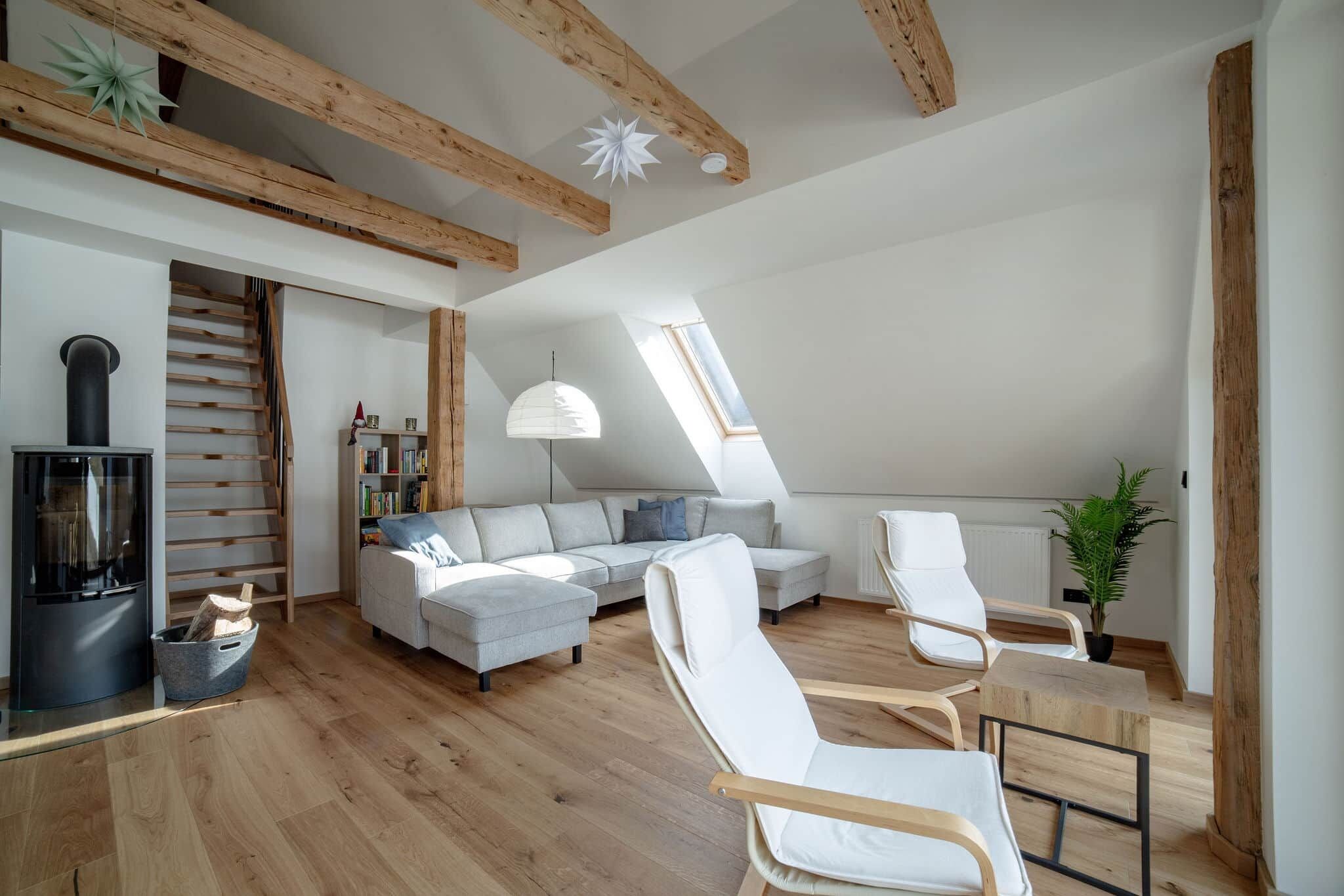 Ein Loft-Wohnraum mit freiliegenden Holzbalken, einem eingebauten Kamin, einer Couch und einem Essbereich.
