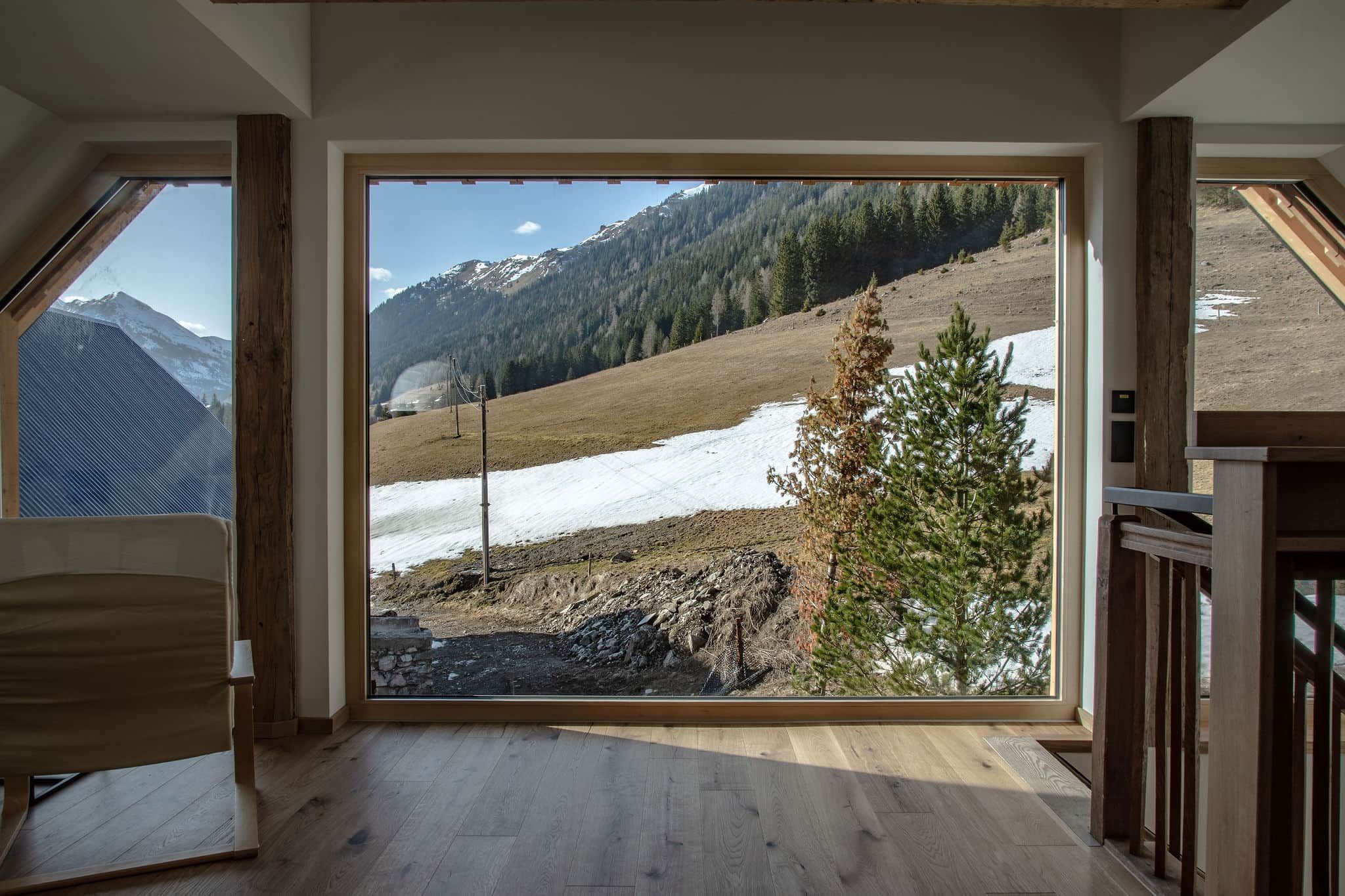 Ein Zimmer mit großem Fenster und Blick auf eine verschneite Landschaft mit Bäumen und Bergen.