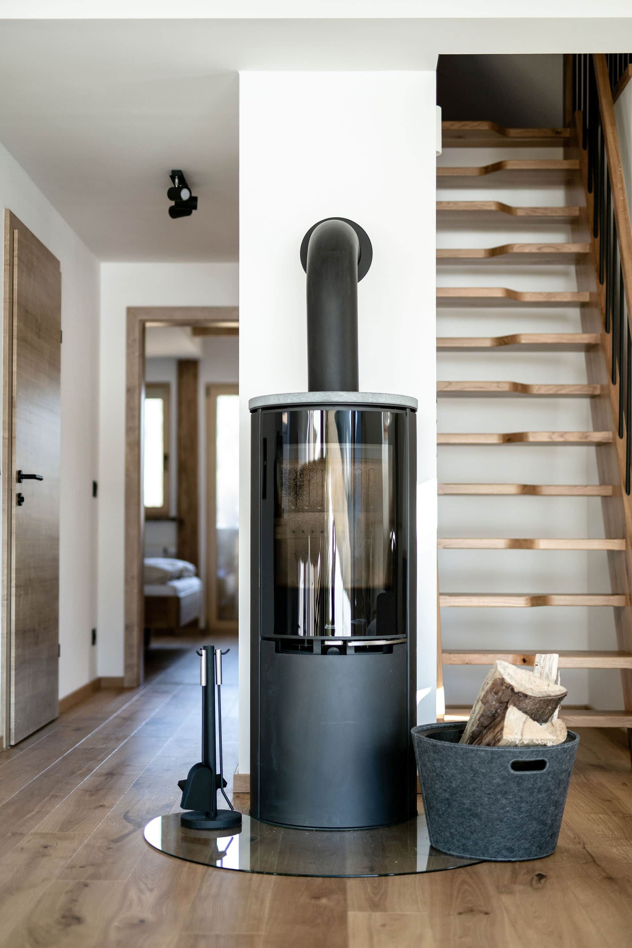Ein modernes Interieur mit Kaminofen, Treppe und einem Gang zu einem weiteren Raum.