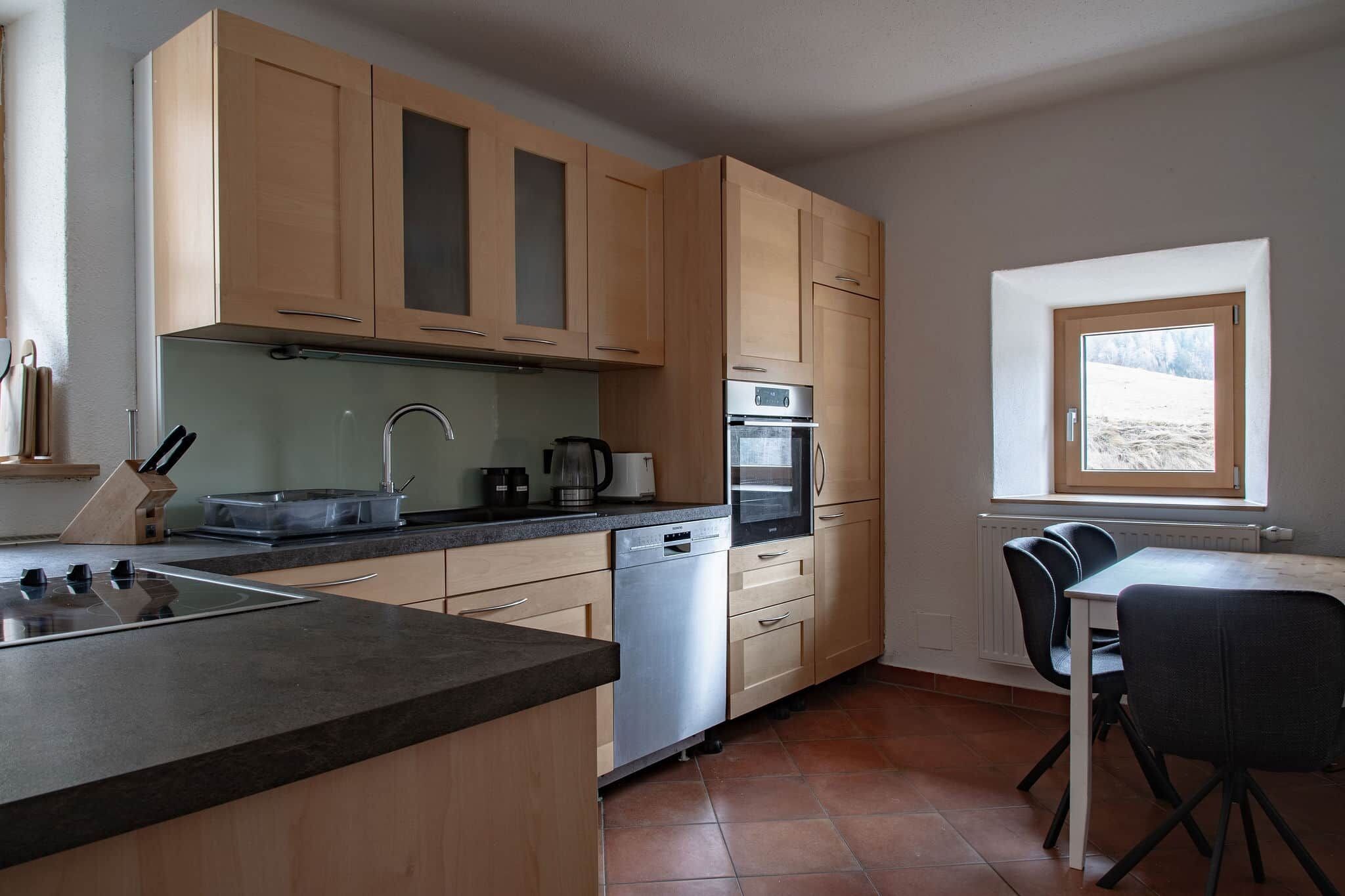 Eine Küche mit Holzausstattung, einem Geschirrspüler, einem Backofen, einer Spüle und einem Fenster mit Blick.