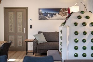 A room with a sofa, a small table, a door with floral designs, and a wall-mounted picture of a mountainous landscape. - Detox Almhaus - chalet in a unique, secluded location (Pusterwald)