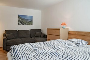 Un dormitorio con una cama, un sofá, una mesita de noche y una lámpara.