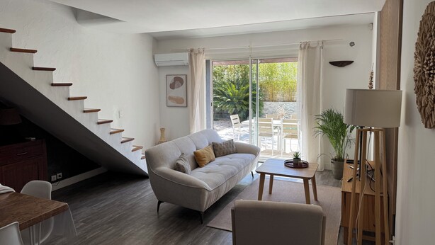 Una sala de estar moderna con un sofá, una mesa de comedor y una escalera.