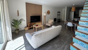 Una sala de estar moderna con sofá, televisor y una escalera con baldosas estampadas.
