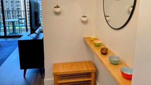 A modern interior with a wooden bench, a mirror, and wall-mounted planters. - Waikiki Banyan Pineapple Suite with AC & Free Parking (Honolulu)
