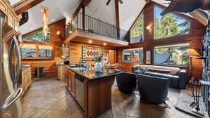A spacious kitchen with a large island, wooden walls, and a stone fireplace. - Grand Elk Chalet by Avantstay Private Beach + Pier + Hot Tub Historic A-frame in Carnelian Bay Near Tahoe City + Hiking Trails (Carnelian Bay)