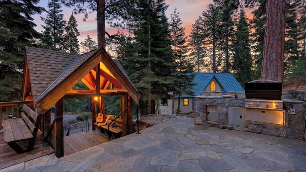 A cabin with a stone patio, a wooden structure with a guitar, and a stone fireplace. - Grand Elk Chalet by Avantstay Private Beach + Pier + Hot Tub Historic A-frame in Carnelian Bay Near Tahoe City + Hiking Trails (Carnelian Bay)