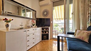 Ein Wohnzimmer mit einer Couch, einem Fernseher, einem weißen Schrank und einem großen Spiegel.