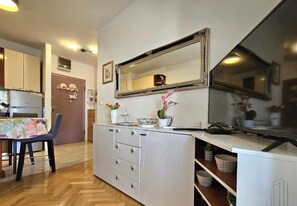 A compact kitchen with a white countertop, a large mirror, and a dining area with a chair and table. - Modern 1BR Apartment – Walk to Old Town Split (Split)