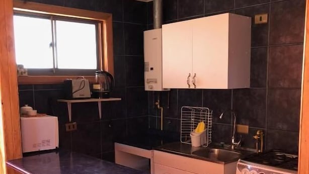 Una cocina con una isla central, sillas de madera, estufa y armarios.