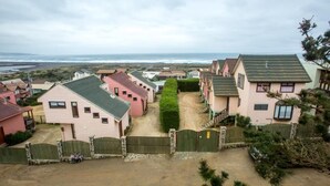 Un área residencial costera con casas, un camino de tierra y vista al océano.