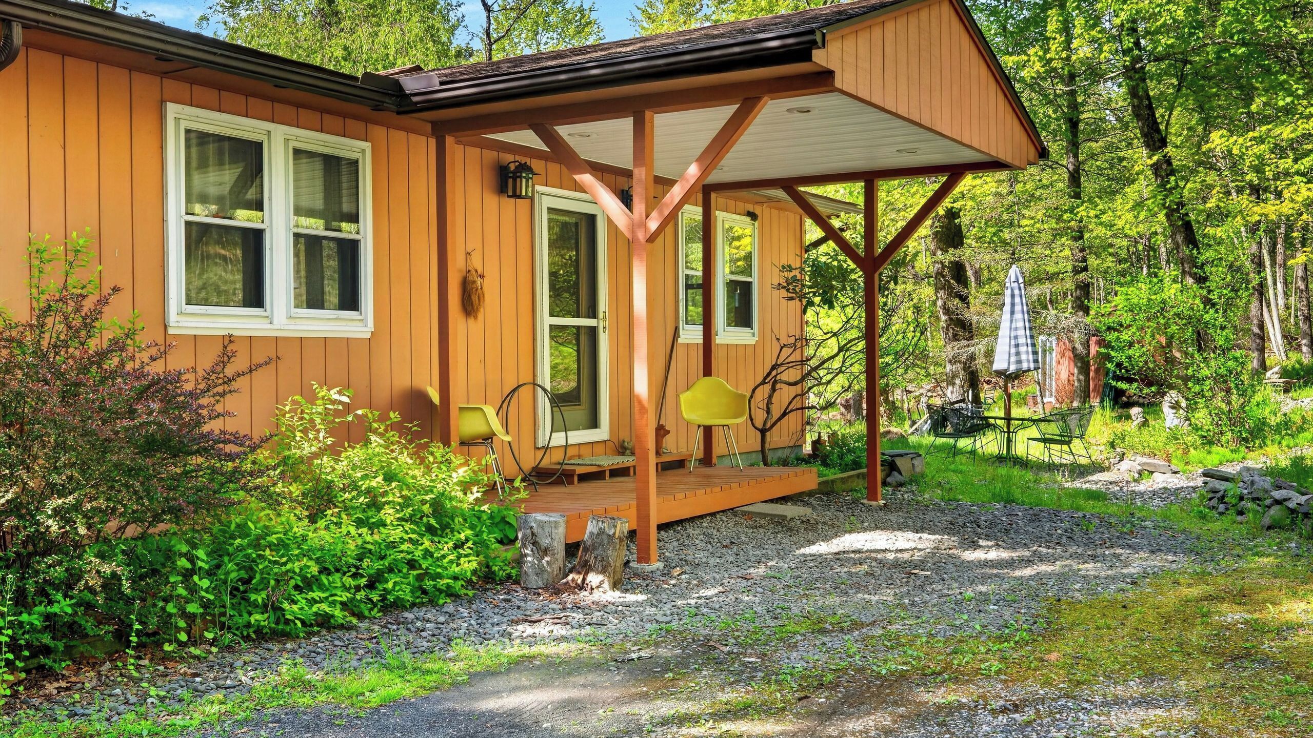 A wooden cabin with a porch, a chair, and a table.