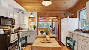 Una cocina moderna con armarios blancos, techo de madera y vistas al exterior.