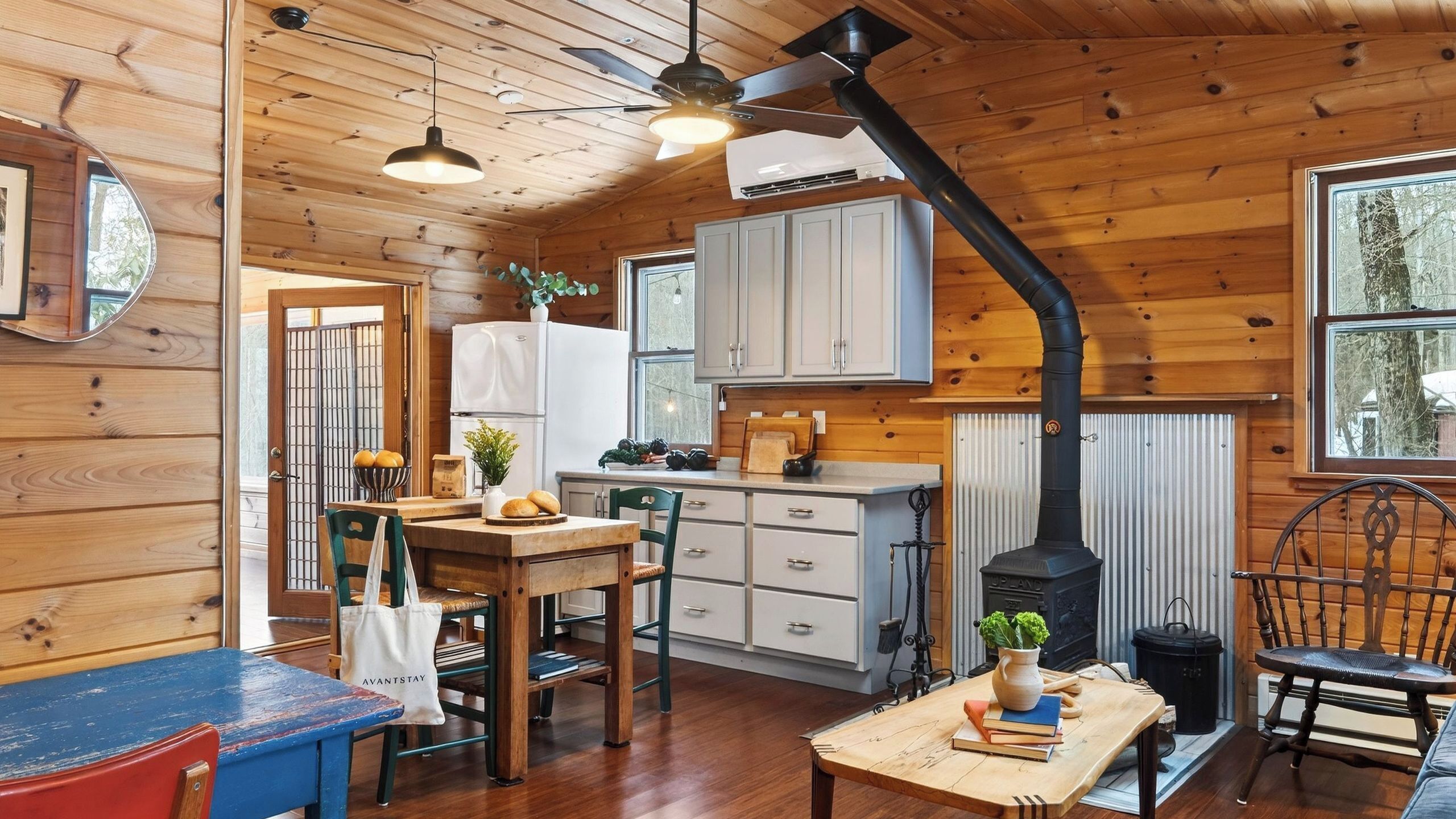 Interior de una cabaña con cocina, comedor y estufa de leña.