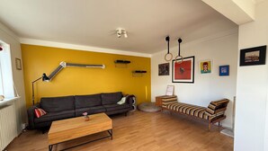 Ein Wohnzimmer mit einer Couch, einem Couchtisch, einer Katzenliege und einer Lampe.