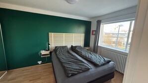 Ein Schlafzimmer mit einem Bett, einem Nachttisch, einem Fenster und einer Heizung.