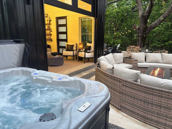 Un bain à remous, des meubles en osier et une vue sur un bâtiment doté d’une porte en verre.