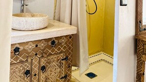 Un baño con un espejo redondo, un lavabo, una cortina de ducha y un armario de madera.