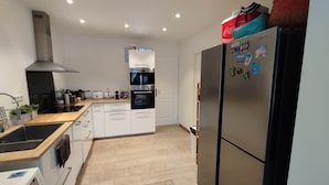 A modern kitchen with a built-in oven, a stainless steel refrigerator, and a washing machine. - Beach house: terrace, relaxation, air conditioning, wifi (Hyères)