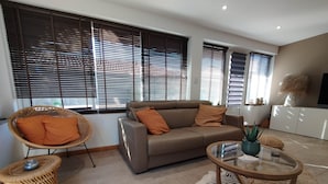 A living room with a sofa, a wicker chair, a glass coffee table, and a zebra-patterned rug. - Beach house: terrace, relaxation, air conditioning, wifi (Hyères)