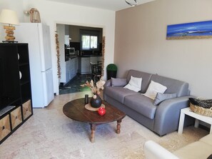 A living room with a grey sofa, a coffee table, a lamp, and a painting on the wall. - Les Palmiers, T2 seaside, bike, air conditioning, terrace (Hyères)