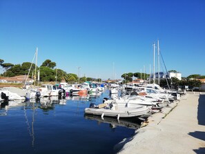 A marina with various boats docked, a clear sky, and buildings in the background. - Les Palmiers, T2 seaside, bike, air conditioning, terrace (Hyères)