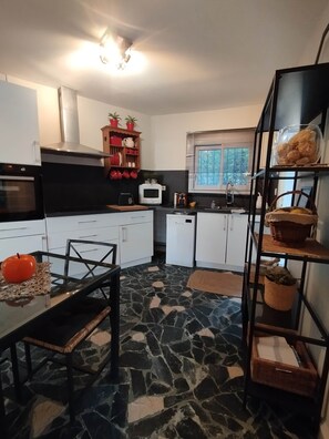 A compact kitchen with a microwave, oven, and a dining area with a table and chairs. - Les Palmiers, T2 seaside, bike, air conditioning, terrace (Hyères)
